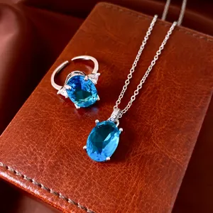 Detail view of oval blue zircon necklace and ring set on brown leather background