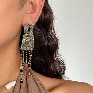 Detailed view of vintage distressed gold tassel earrings featuring waterdrop acrylic beads