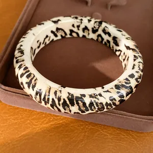 Detailaufnahme eines klobigen Harz-Armreifs mit Leopardenmuster und glänzendem Finish