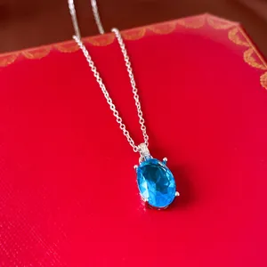 Macro detail of blue oval zircon pendant necklace on a luxury red jewelry box