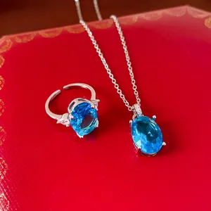 Detailed close-up of vintage style oval blue zircon necklace and ring set on red box