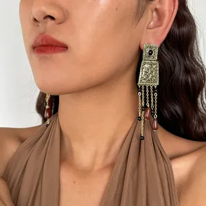 Close-up of vintage gold metal earrings with acrylic teardrop tassels worn by model.