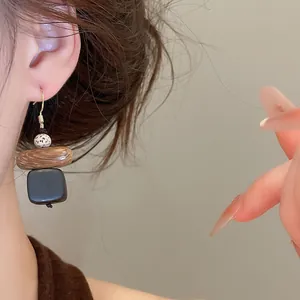 Gros plan sur des boucles d'oreilles pendantes géométriques en bois de style ethnique