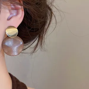 Gros plan de boucles d'oreilles vintage avec métal doré et disques en bois brun.