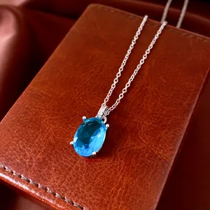 Detailed close-up of an elegant oval blue zircon pendant necklace on a brown box