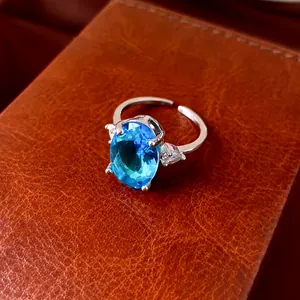 Close-up of elegant oval blue zircon ring on a textured leather surface
