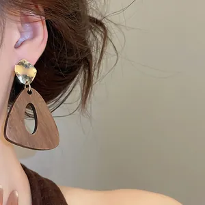 Gros plan de boucles d'oreilles géométriques en bois avec détails en métal doré martelé