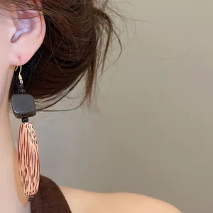 Gros plan détaillé de boucles d'oreilles ethniques vintage en bois géométriques portées
