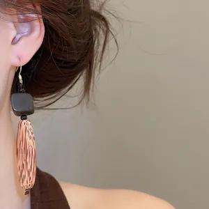 Détail rapproché de boucles d'oreilles ethniques en bois portées par un mannequin asiatique