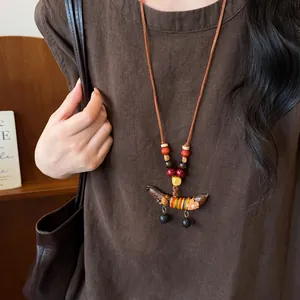 Detail van etnische ketting met erwtenhanger en houten kralen op bruine linnen jurk