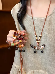 Detailansicht einer ethnischen Holzperlenkette mit Erbsenanhänger im Vintage-Stil an einem Model