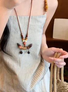 Detailaufnahme einer ethnischen Holzperlenkette mit einem bunten Erbsen-Anhänger