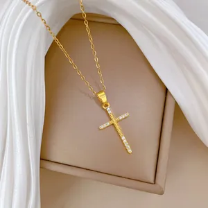 Gros plan d'un collier avec pendentif croix en acier titane doré et strass brillants.