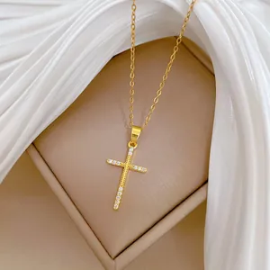 Détail d'un collier avec pendentif croix en or minimaliste orné de zircones scintillants.