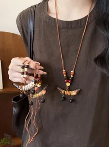 Detailansicht einer Holzhalskette im Ethno-Stil mit Erbsenanhänger an einem Model.