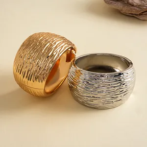 Detailopname van metalen armbanden met een rimpelige textuur in goud en zilver finish