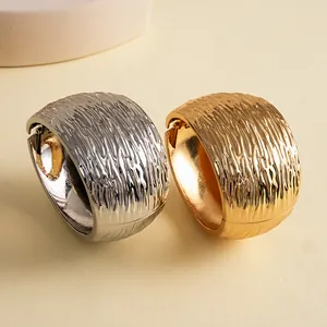 Detailopname van gouden en zilveren chunky armbanden met een gerimpelde textuur.
