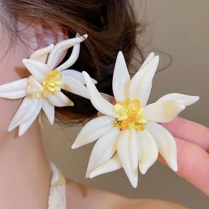 Detailansicht weißer Harzblumenohrringe mit gelber Kristallmitte an einem Model-Ohr
