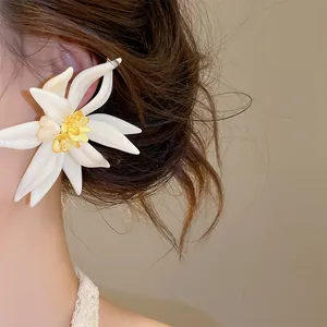 Detailaufnahme eines eleganten Harzblumenohrrings mit Kristallmitte am Ohr des Modells