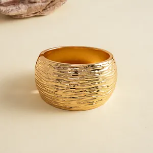 Detailweergave van gouden brede armband met unieke geplooide metaaltextuur.