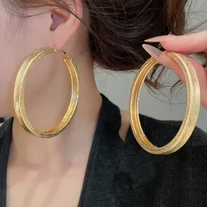 Close-up detail of oversized gold hoop earrings with fine shimmering textured finish