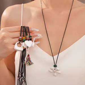 Collana in ceramica fatta a mano con ciondoli a fiore, uccello e cuore su cordini.