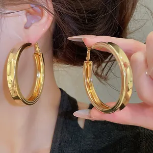 Detail view of chunky gold hoop earrings with polished finish on model's ear