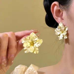 Detailansicht der eleganten, cremefarbenen Kamelienblüten-Ohrstecker an einem Modell.