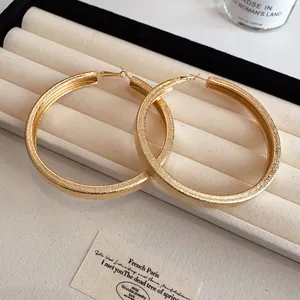 Detailed view of oversized gold hoop earrings with textured finish on jewelry tray