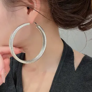 Detail shot of oversized textured silver hoop earrings worn by an elegant model