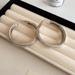 Detail view of chunky silver hoop earrings with a smooth polished finish