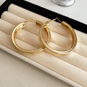 Detailed close-up view of elegant large gold hoop earrings displayed in a cream jewelry box