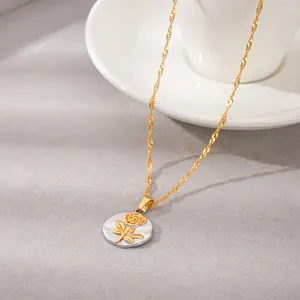 Macrodetail van de gouden roos in reliëf op een ronde zilveren roestvrijstalen hanger