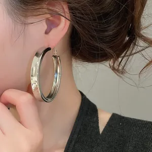 Close-up of a large chunky silver hoop earring worn by a model for a trendy and stylish look.