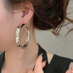 Close-up of a model wearing large silver chunky hoop earrings for a stylish look