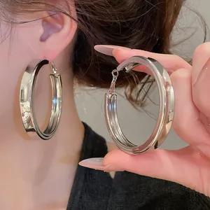 Close-up detail of large silver-toned hoop earrings with a smooth polished finish