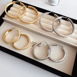 Close-up of stylish gold and silver oversized hoop earrings with smooth and textured finishes