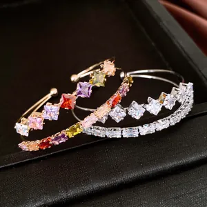Dettaglio di tre bracciali aperti placcati in oro 18k con zirconi quadrati colorati