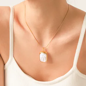 Gros plan d'un collier avec pendentif perle baroque sur une fine chaîne dorée.