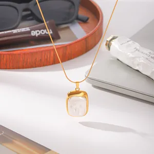 Gros plan d'un collier doré avec pendentif en perle baroque sur un plateau décor