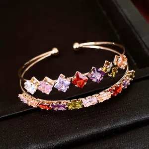 Primo piano dell'elegante bracciale rigido in oro a due strati con zirconi quadrati colorati