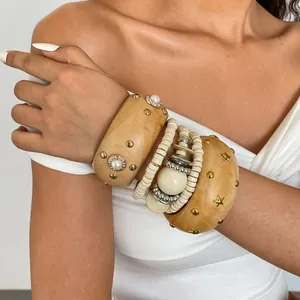 Close-up van etnische houten armbanden met gouden studs en sterren op model
