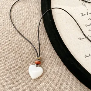Vista dettagliata di una collana con ciondolo a cuore bianco e perline su cordino nero