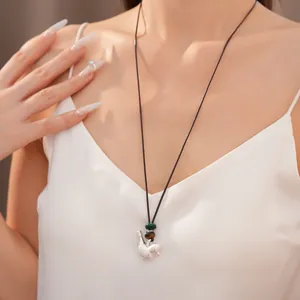 Elegante collana con ciondolo a uccello in argento e perline colorate su una modella.