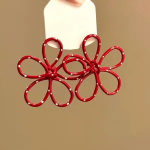 Primo piano che mostra la finitura rossa lucida e i pois bianchi sugli orecchini a fiore