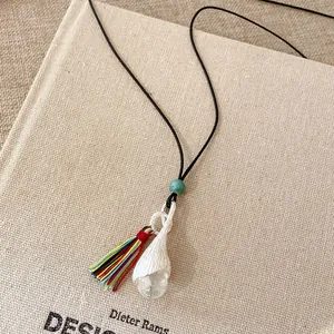 Vista dettagliata della collana con ciondolo a fiore in ceramica e nappina colorata