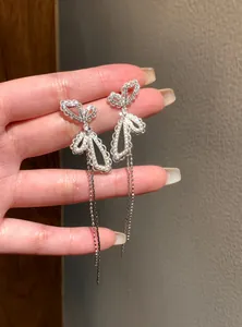Nahaufnahme von eleganten silbernen Schmetterlingsohrringen mit Perlenquasten.
