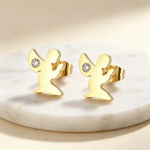 Vue détaillée de boucles d'oreilles ange dorées avec cristal sur un socle en marbre blanc