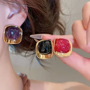 Vue détaillée de boucles d'oreilles carrées en acrylique violet, noir et rouge avec cadre doré