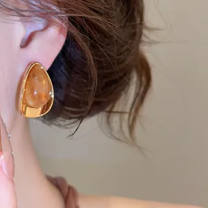 Vue détaillée d'une boucle d'oreille élégante en acrylique ambré et métal doré.